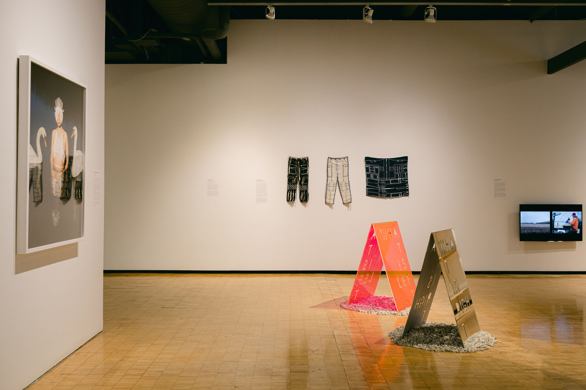 Mixed media art including textile pants, a photo, and text-based sculptures