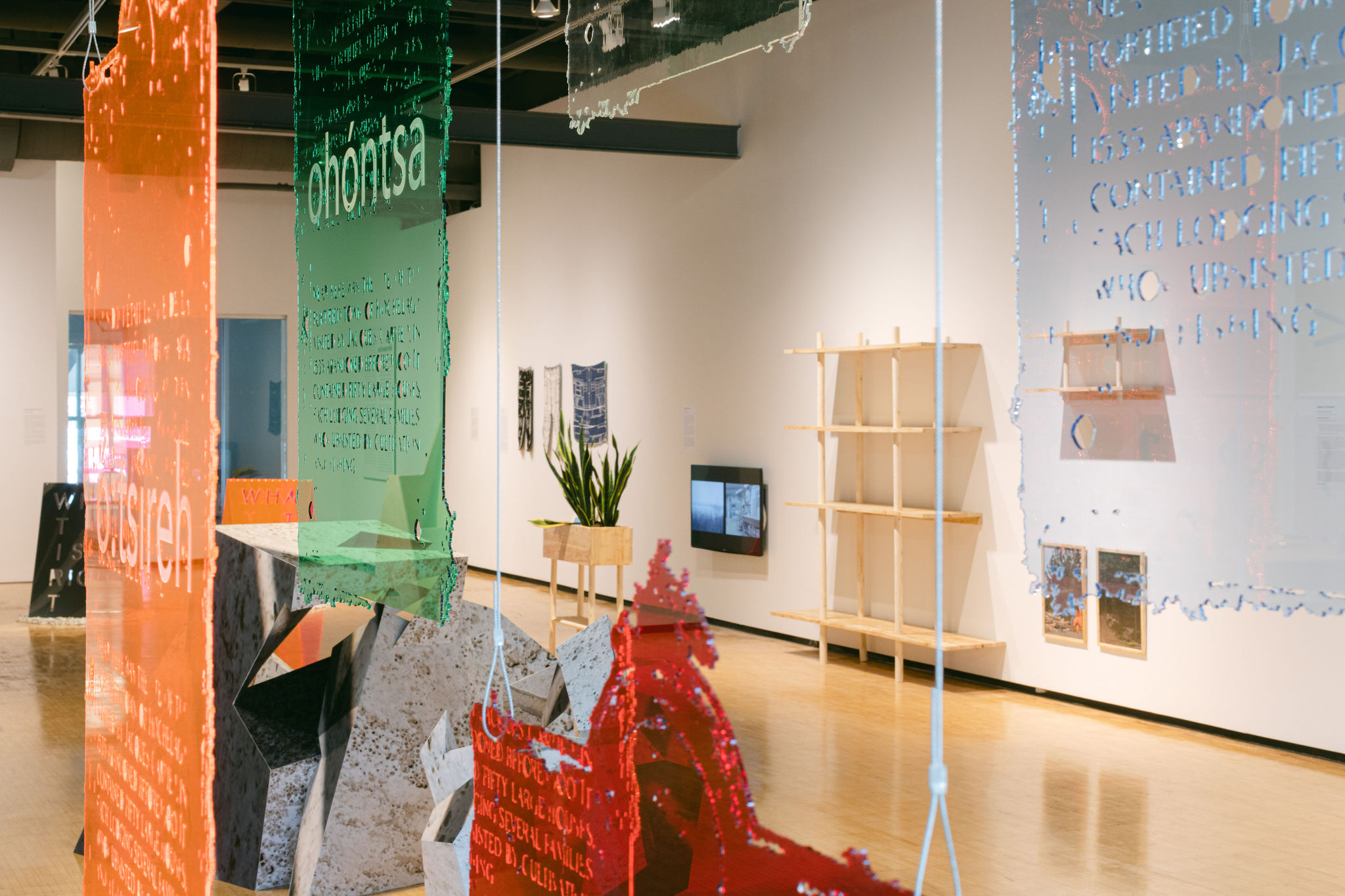 Hanging translucent panels with text, seen through a gallery space