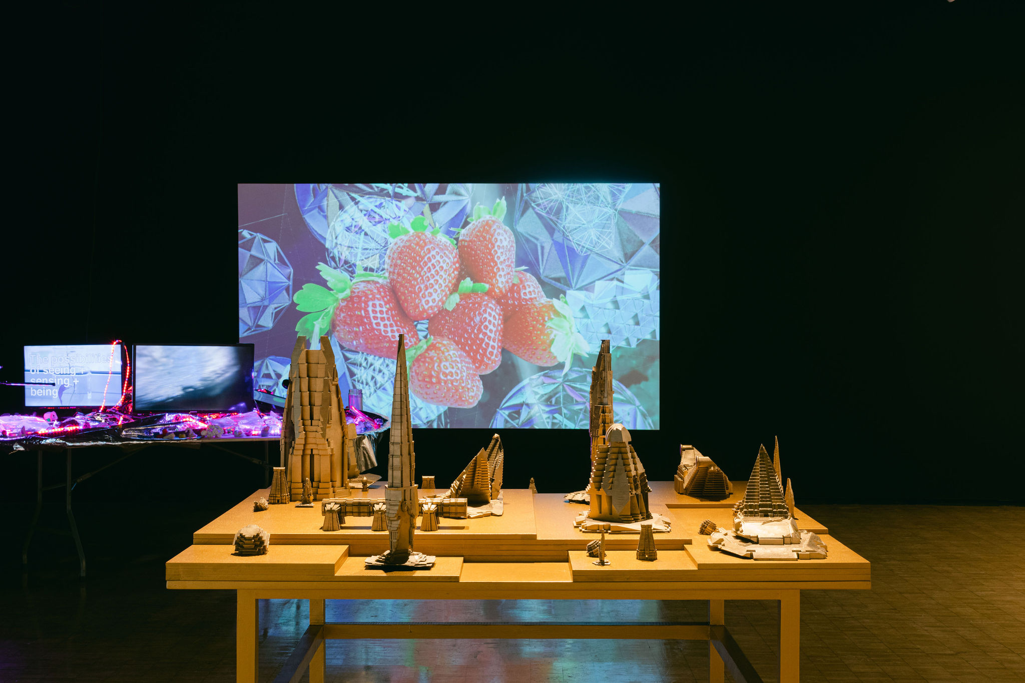 Cardboard architectural models and strawberries projected on a screen
