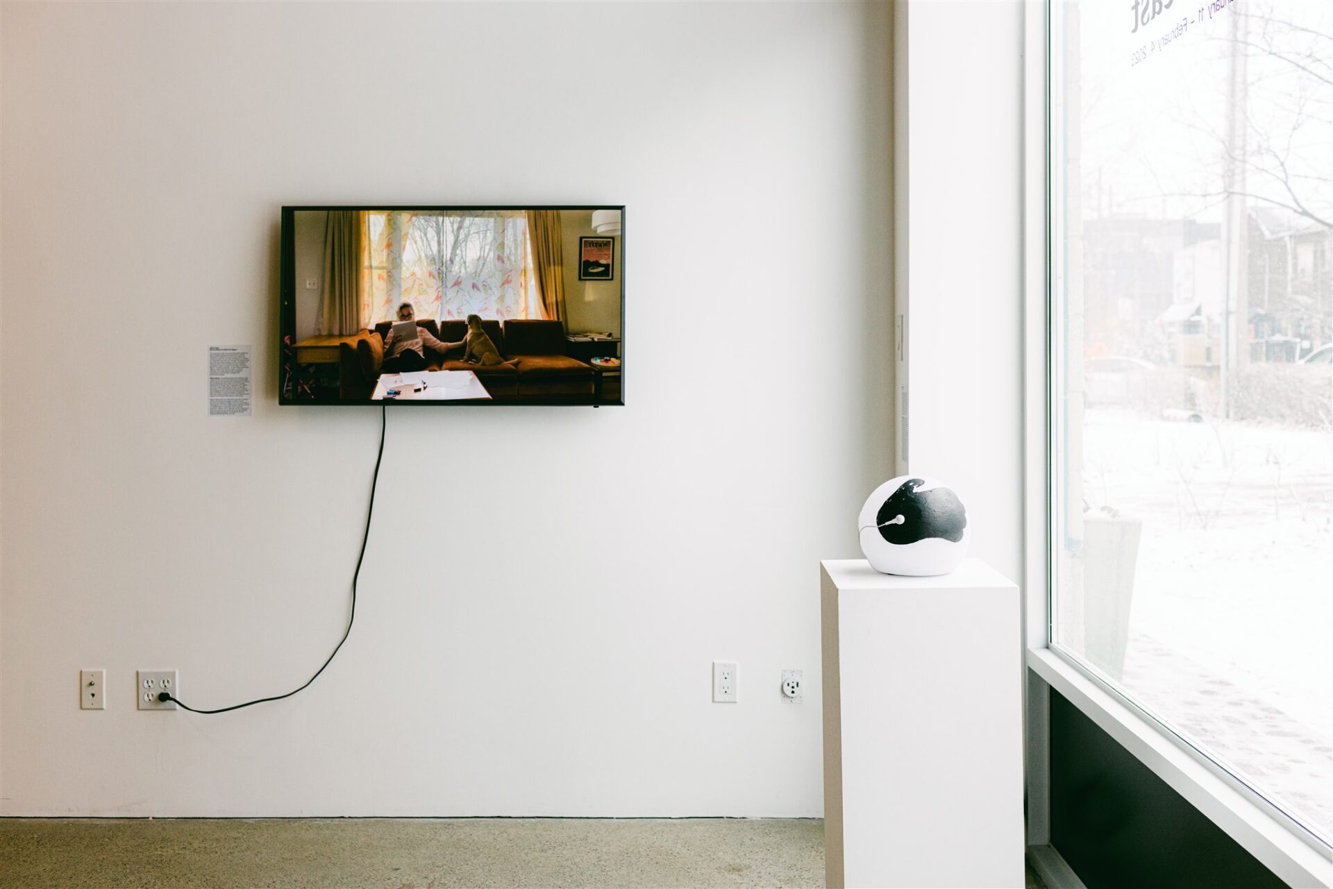 Television screen showing people on a couch, next to a black and white globe sculpture
