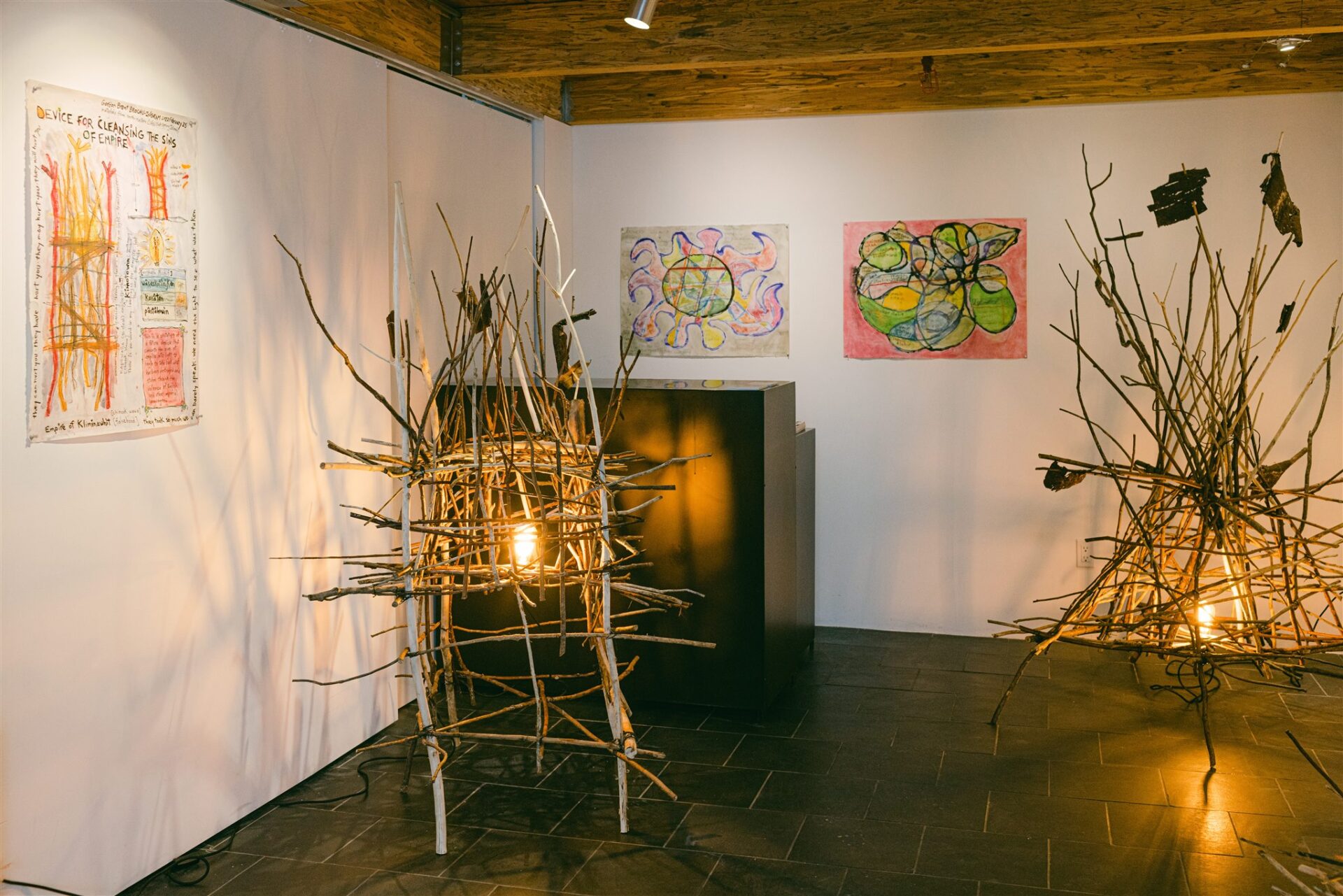 Twig structures lit from inside with colorful abstract drawings on walls