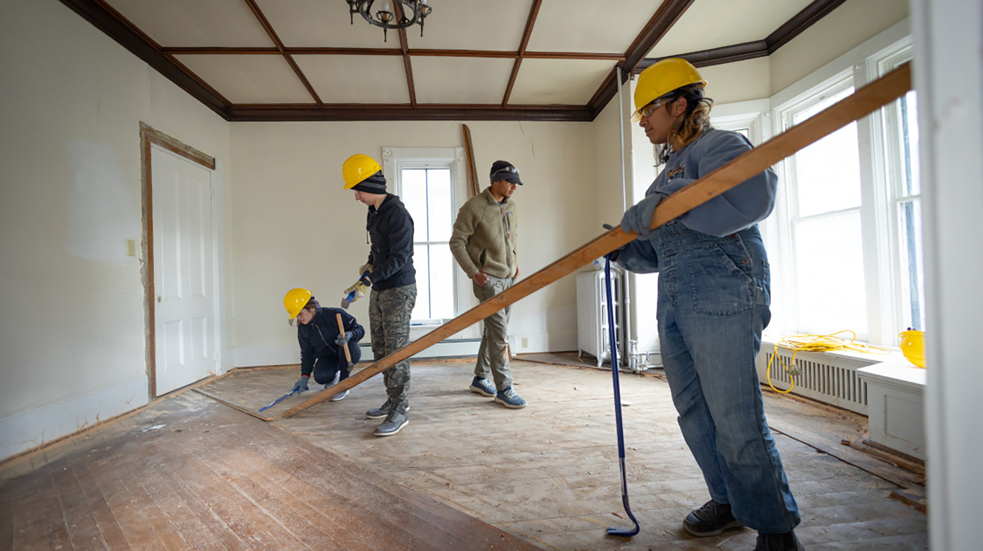 3 people in yellow hard hats deconstructing a room