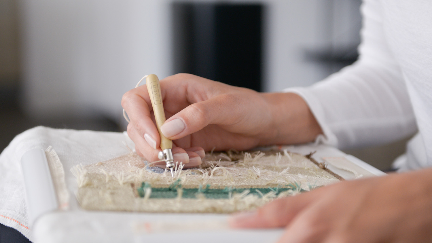 Hands in the process of doing punch needle work.