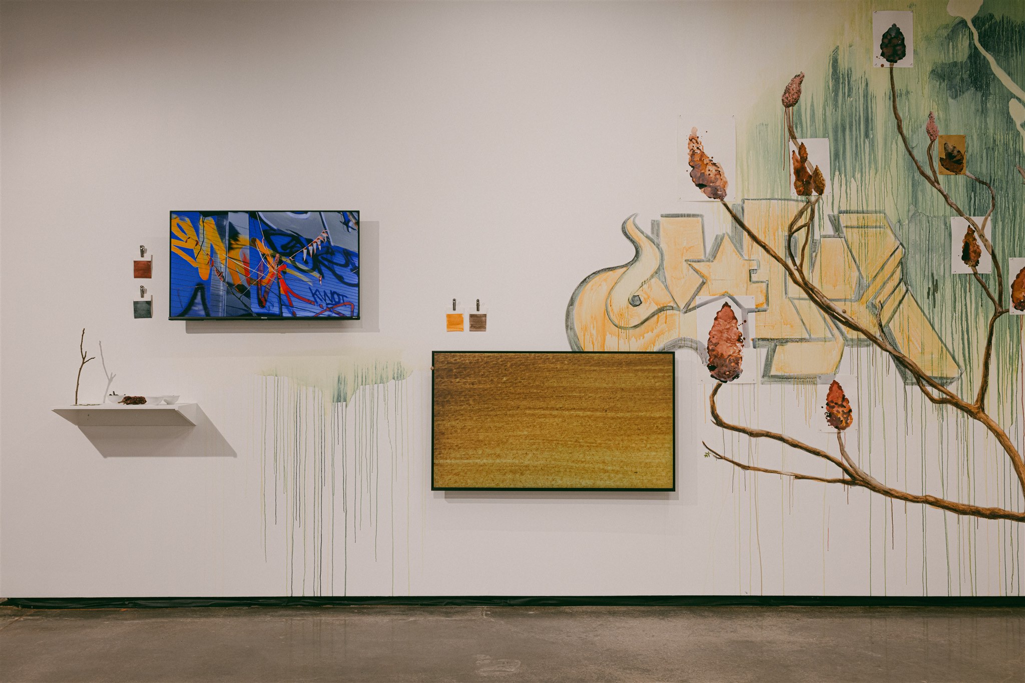 Close-up of mural with videos, drawings, and small materials on a wall