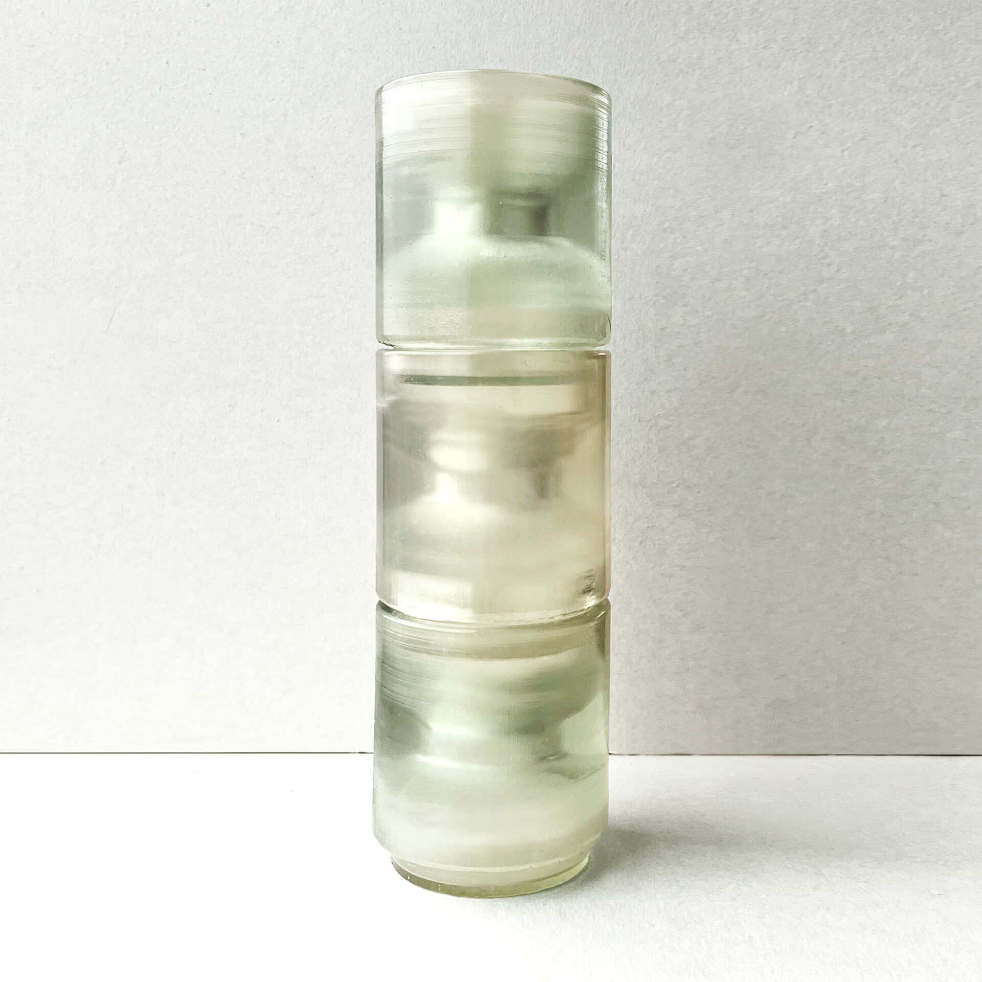 Three translucent glasses stacked on top of each other against a plain grey background