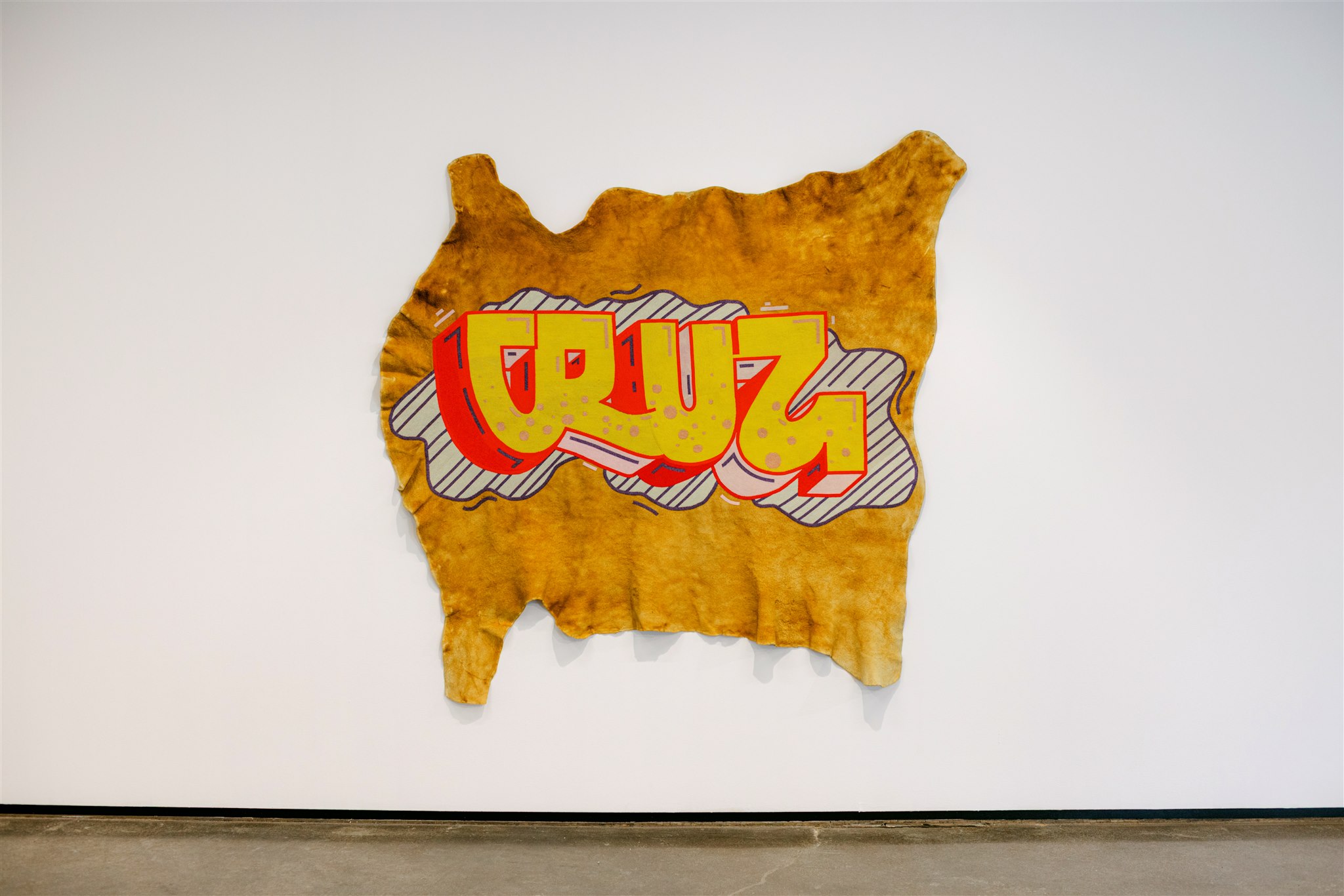 Graffiti-style beadwork with the word "CRUZ" in bold, yellow and red beads on traditionally tanned moose hide.