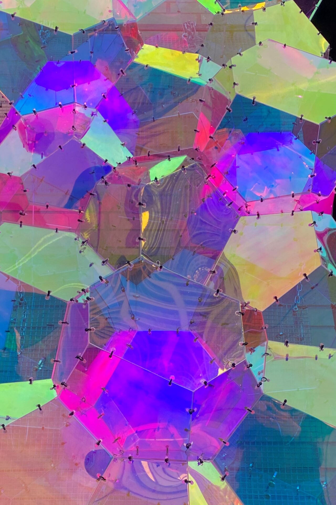 Photograph of detail of sculpture made of geometric shapes, in pinks, blues, purples, yellows and greens,