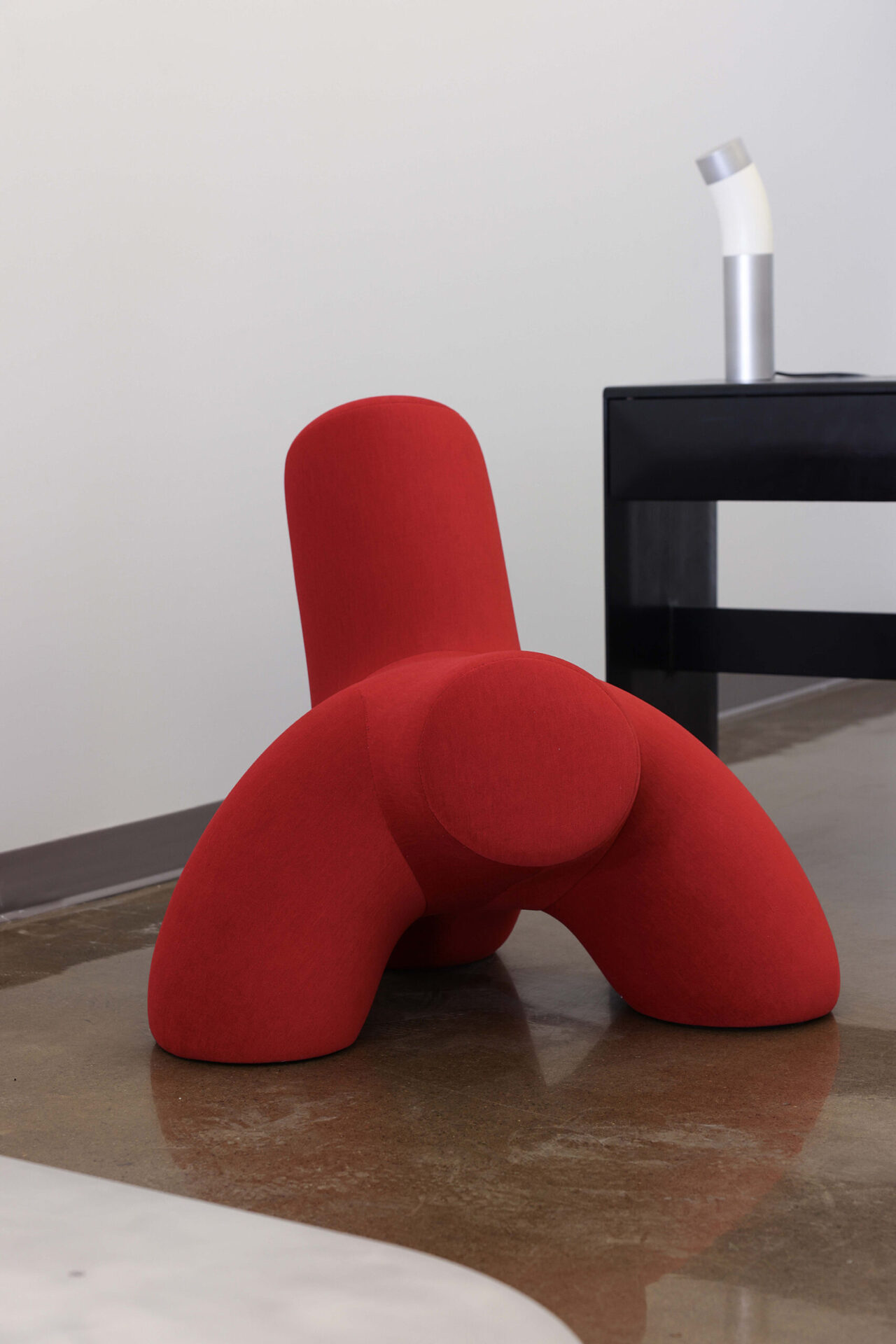 red lounge chair with a black desk behind