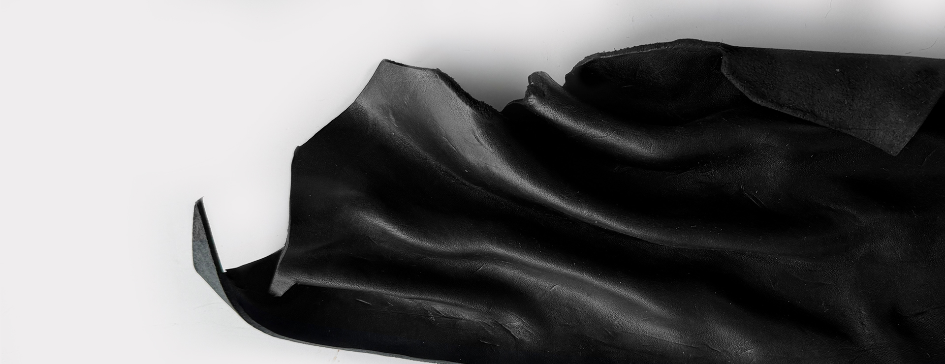 Sculpted piece of black leather against white background.