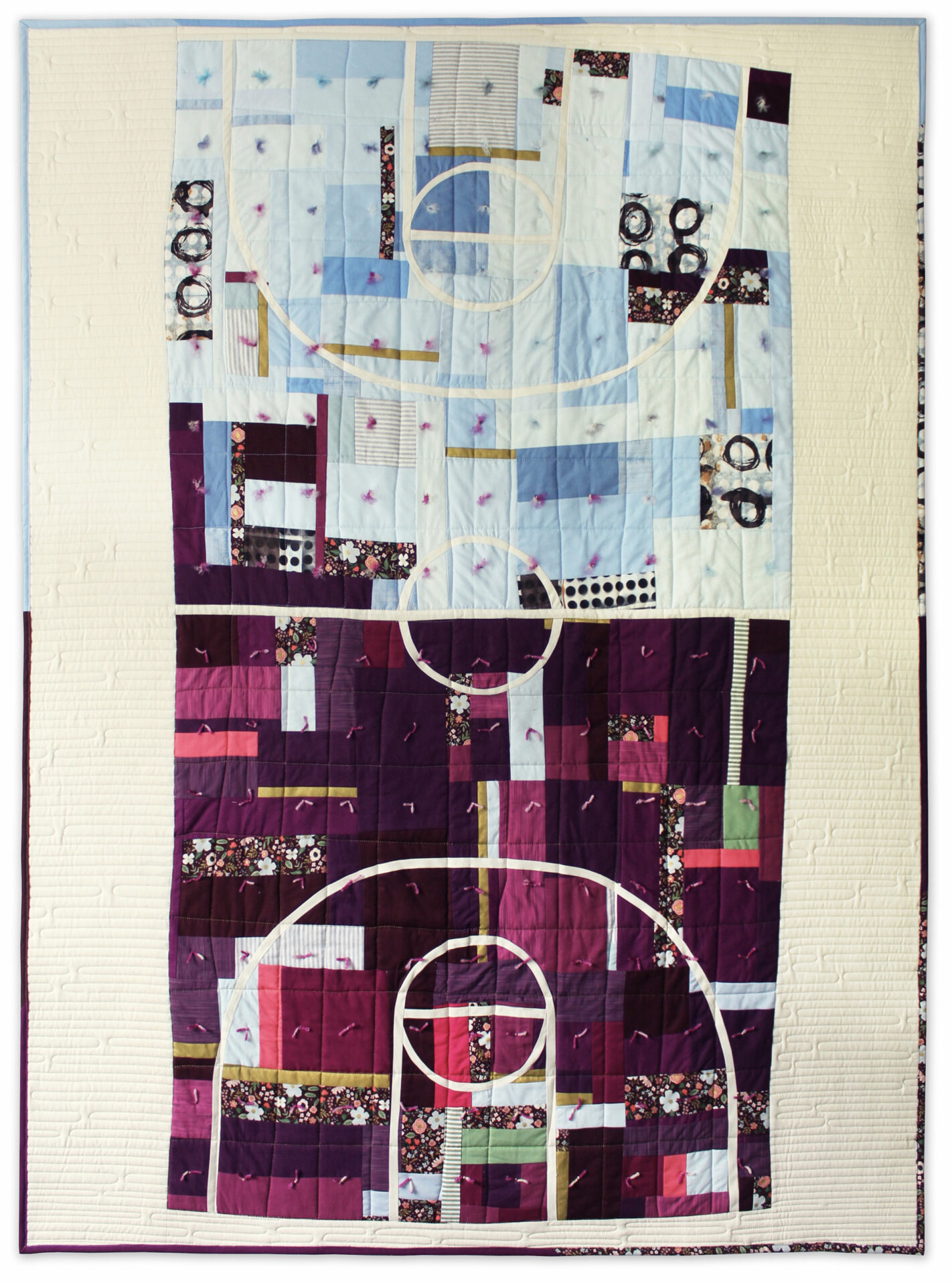 A quilt featuring a patchwork basketball court, half in light blue and half in purple with a broad white border.