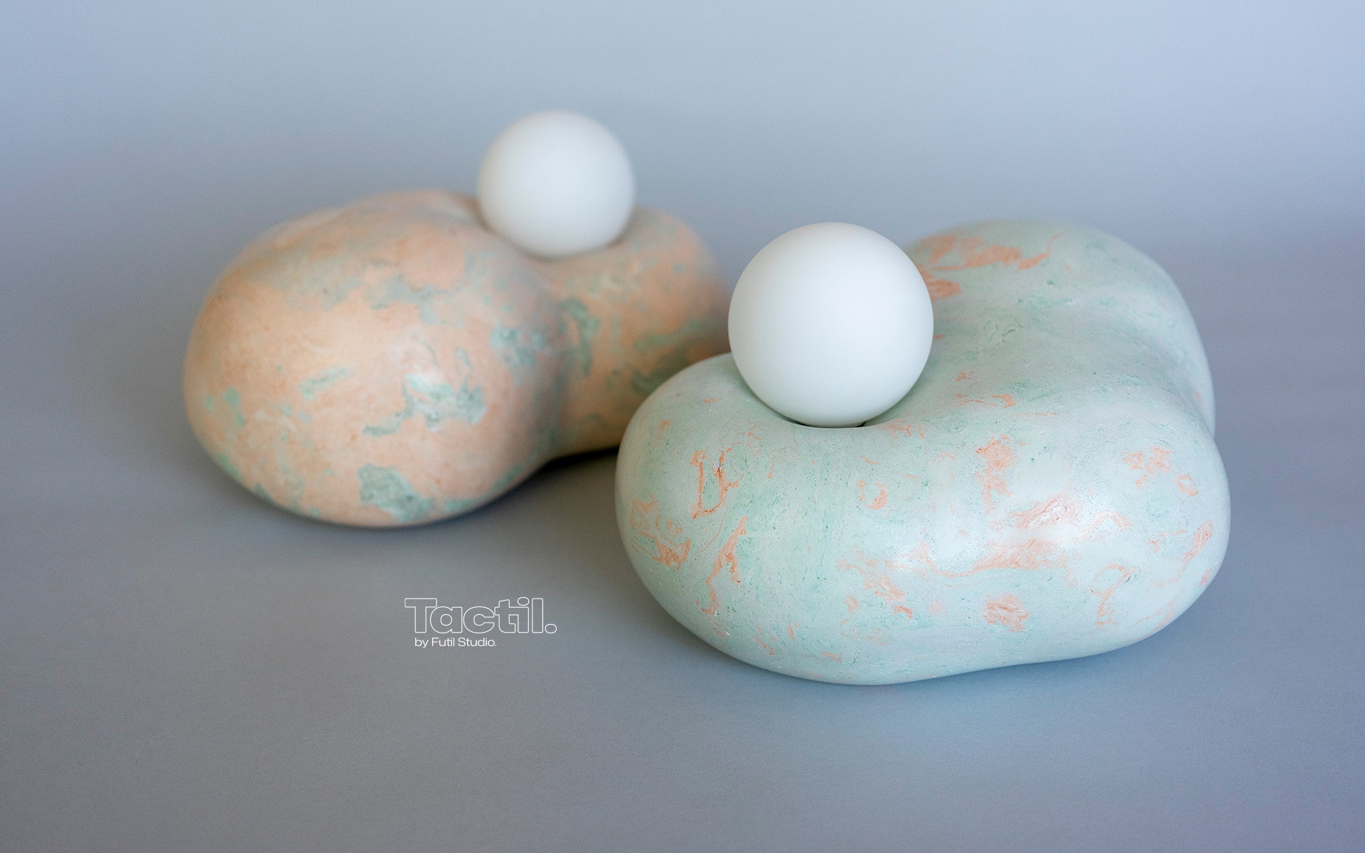 Dream Collector duo table lamp. An ethereal sculptural lighting piece that captures dreams in its organic embrace. Two fluid forms nestle together with luminous spheres that create a mesmerizing interplay of light and shadow. Each Dream Collector features unique scagliola patterns in soft coral and mint tones, transforming any space into a sanctuary of gentle illumination.