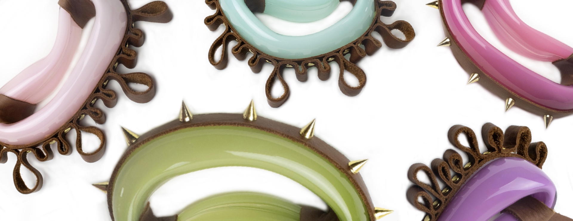 arched blown glass forms in pinks, greens, and blues and purple, with ruffled brown leather and gold spike details.