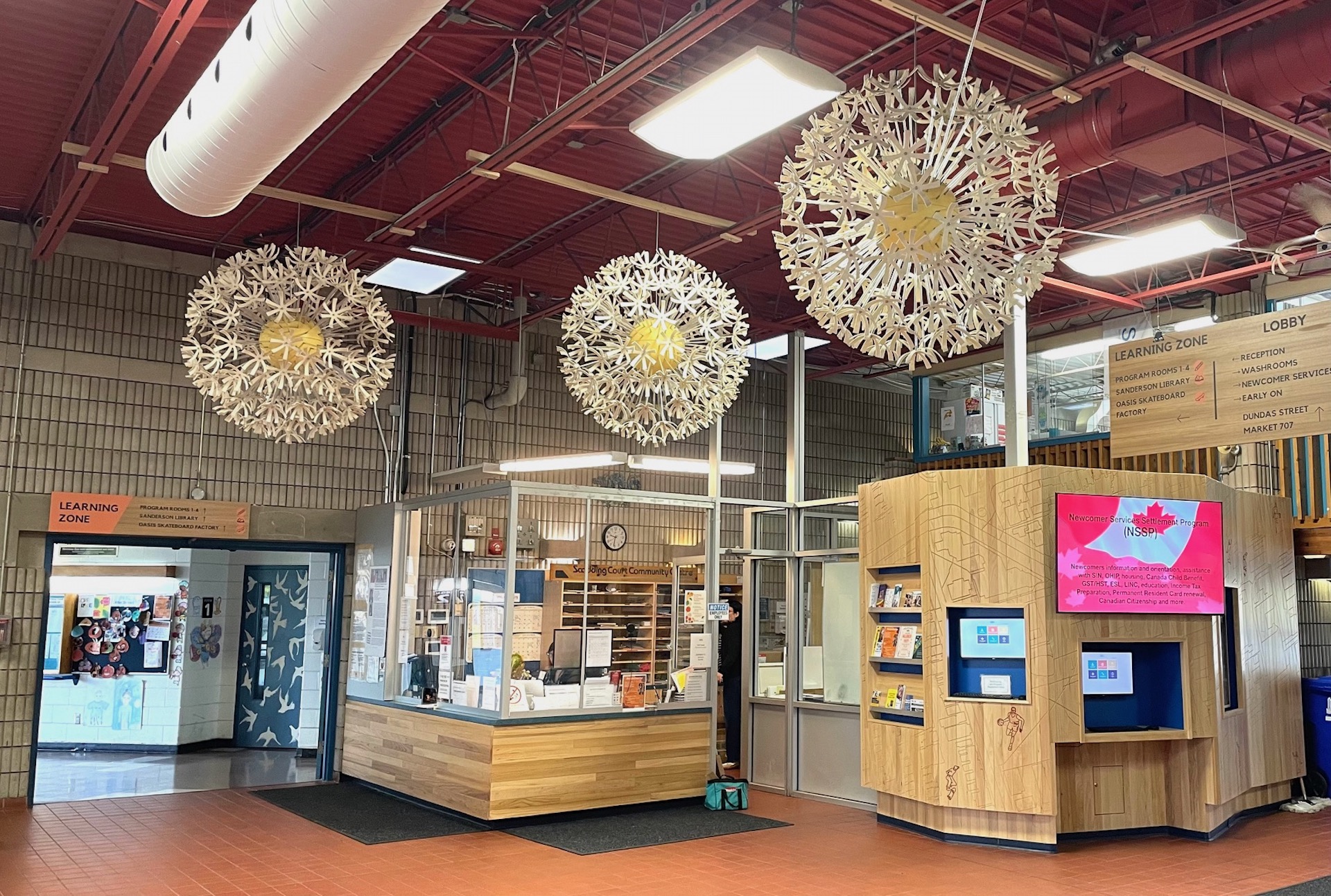 Reception area showing dandelion sculptures overhead, the elm clad reception desk and the entryway wall.