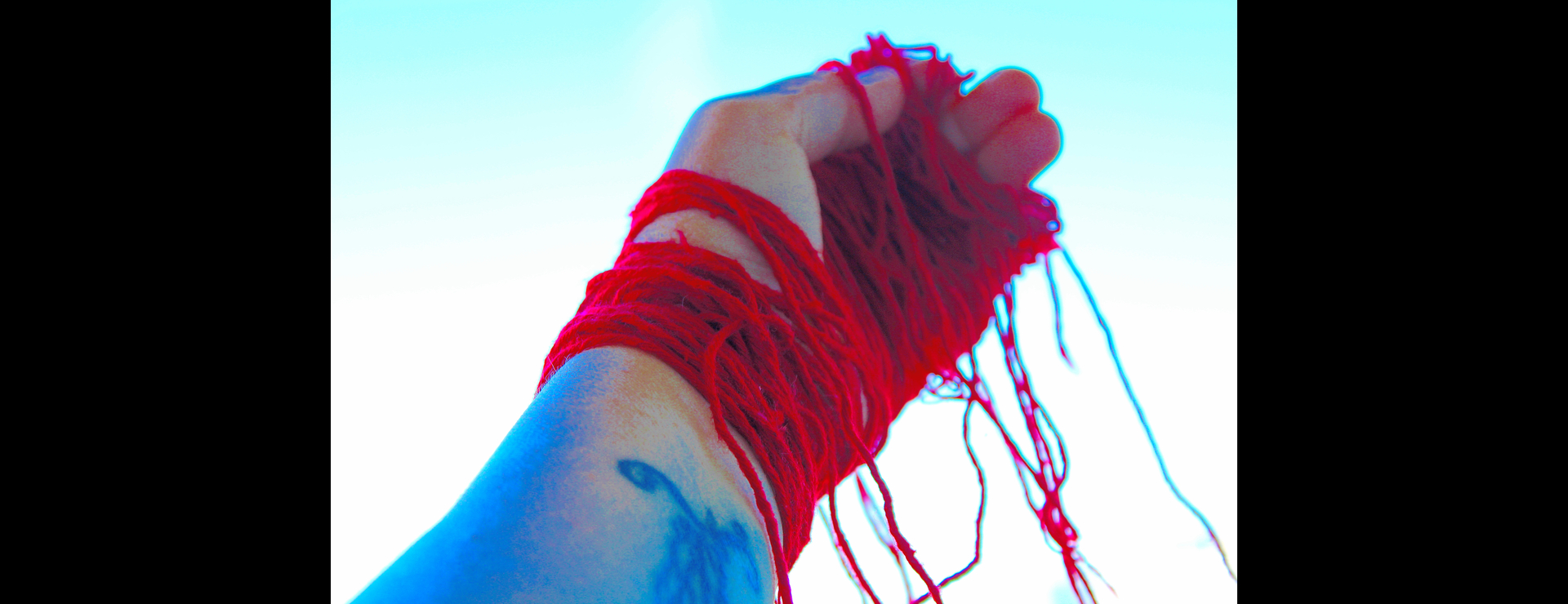 Red yarn on an out stretched hand.
