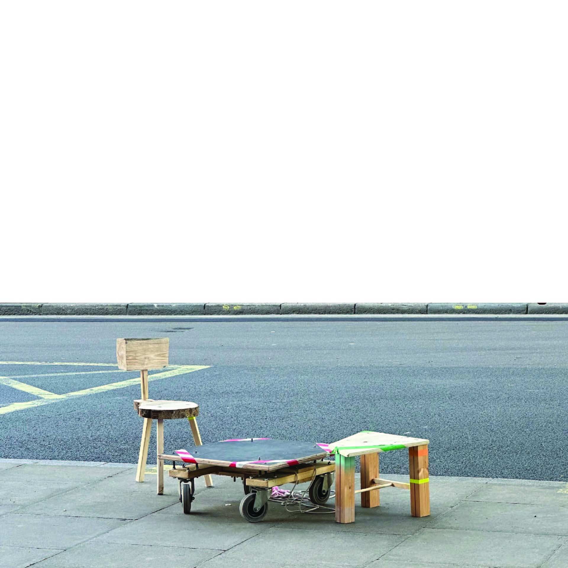 A wooden chair, a low wheeled platform, and a small table on a sidewalk beside an empty street.