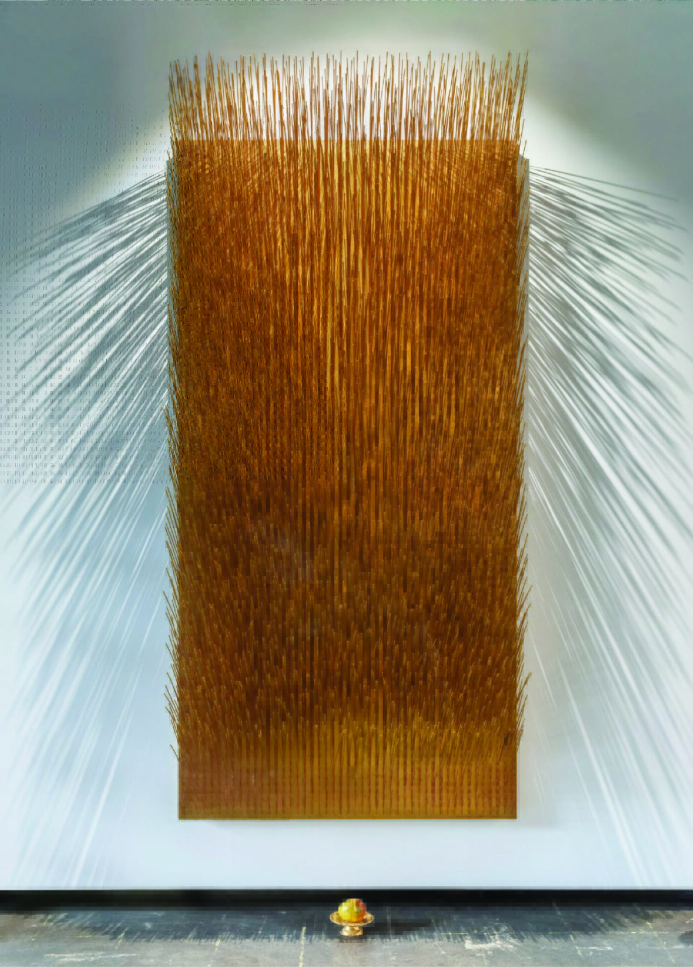 Large golden board with many upright sticks casting long shadows; a small gold bowl sits below.