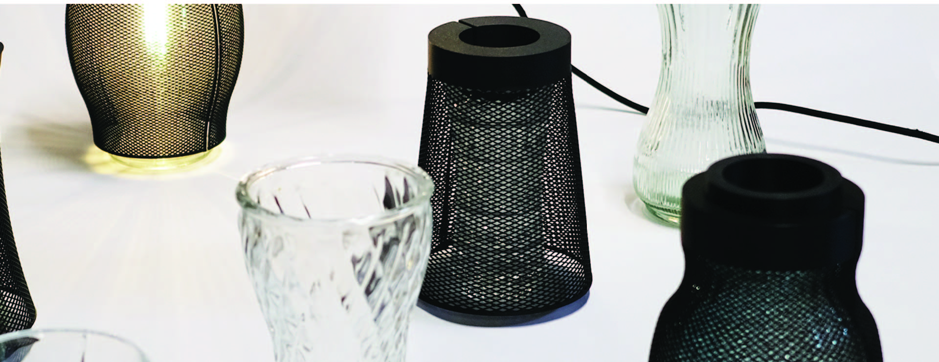 Five individual lamps, each made from a glass vase and a 3D-printed mesh.