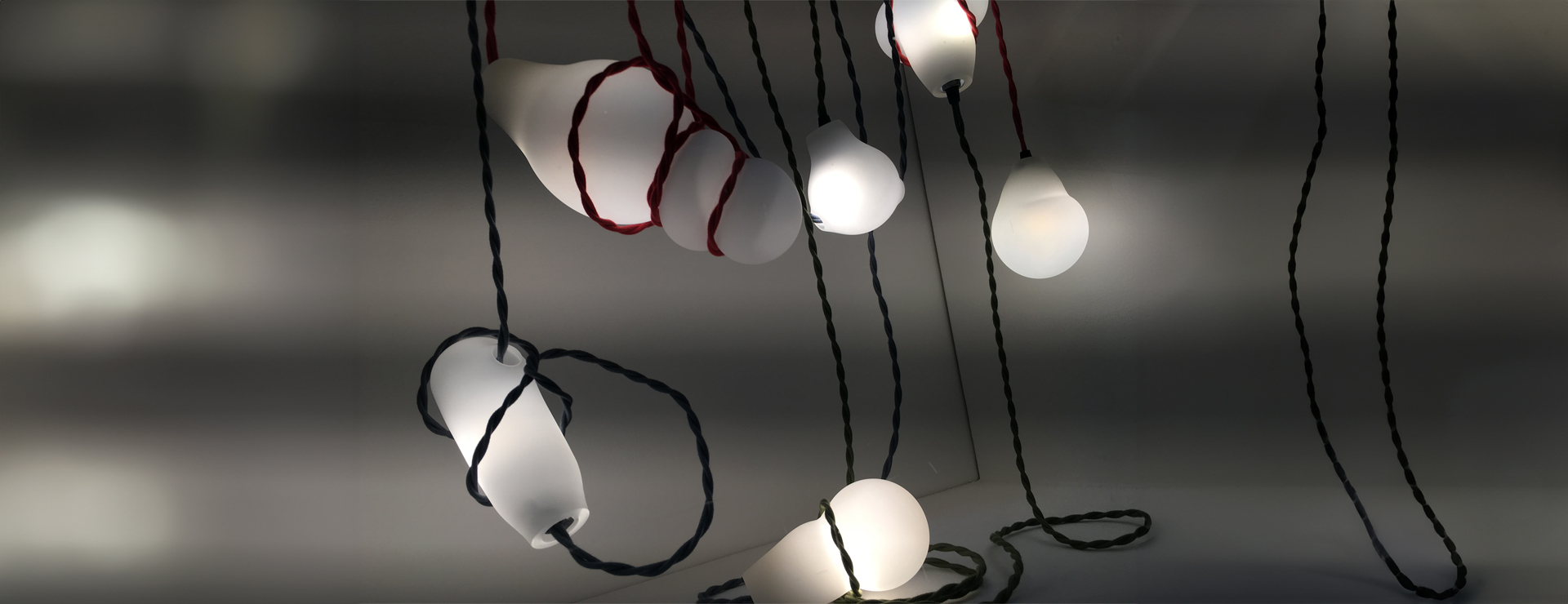 A cluster of hand blown white glass suspended with colourful cord