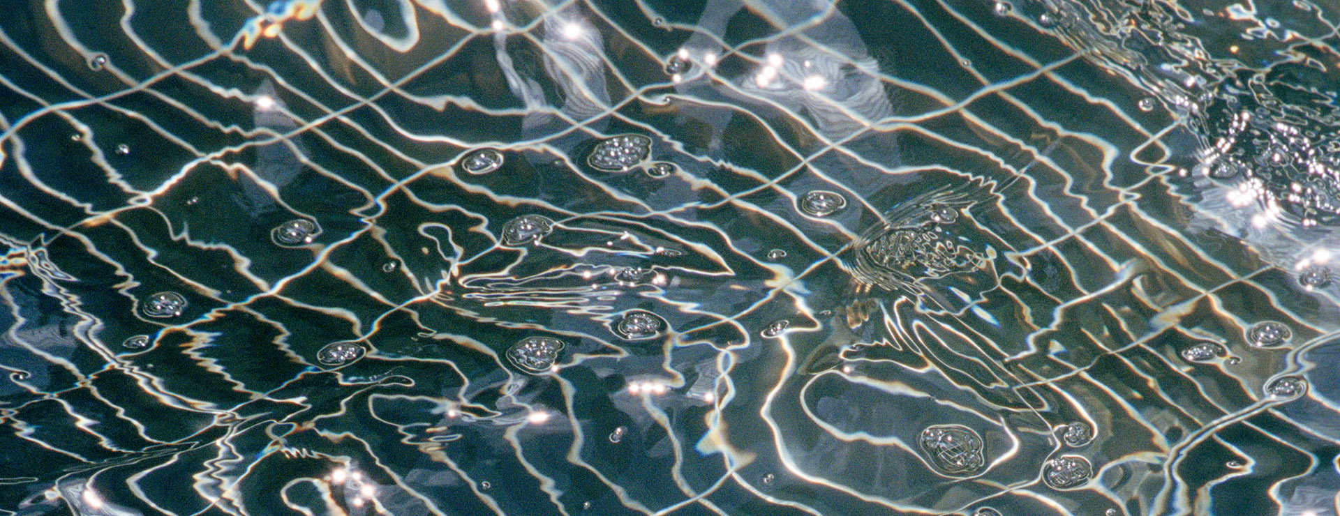 A dark body of water with bubbles and ripples, reflecting a grid.
