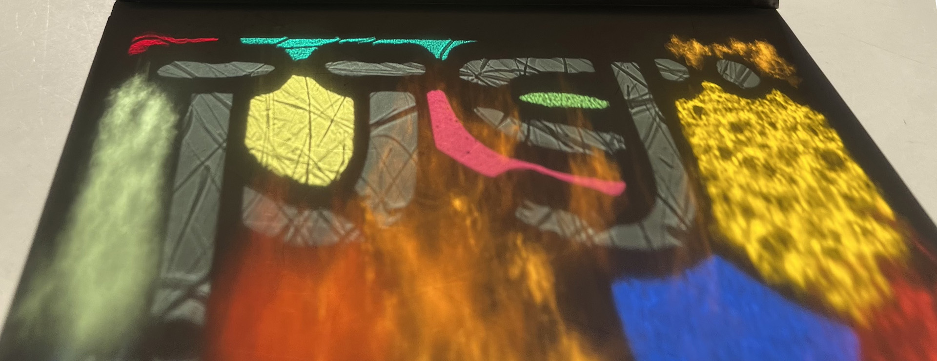 A typographical stained glass refraction featuring various colours and textures of glass.