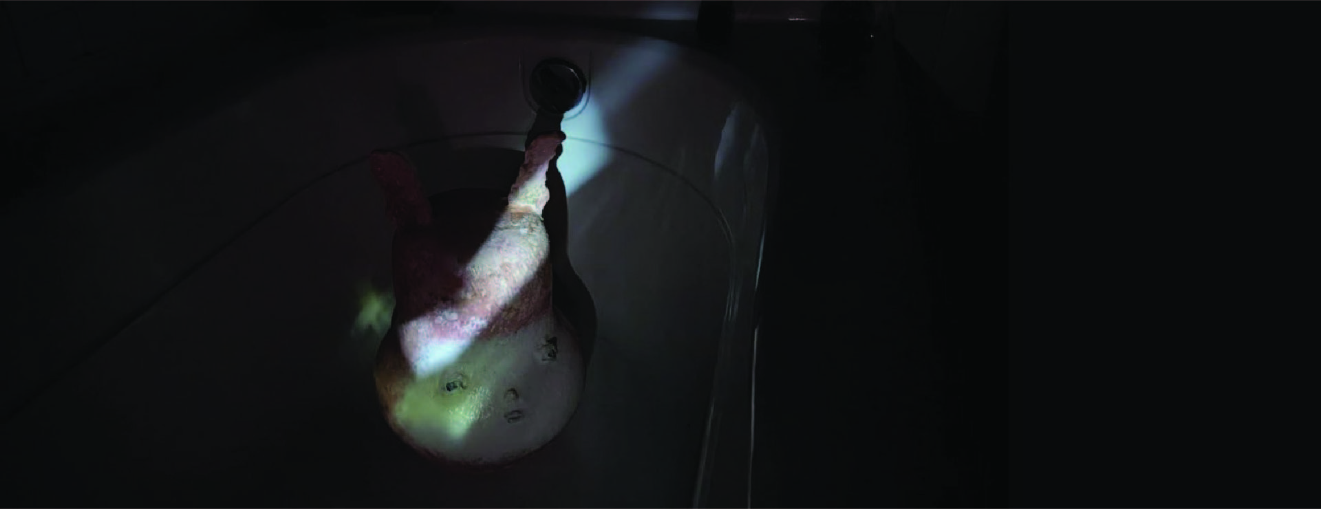 A red bunny-like creature in the dark, illuminated by a phone flashlight. 