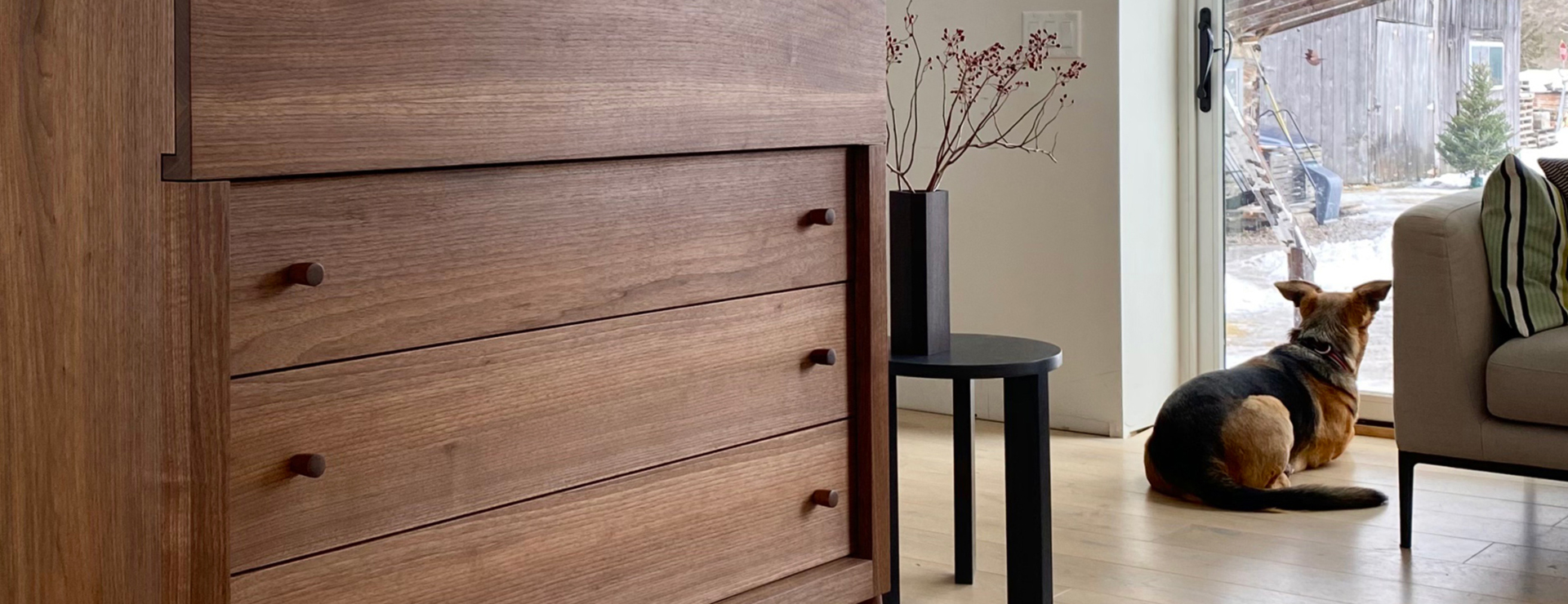 partial 3/4 view of a dresser with a small table and dog beside it