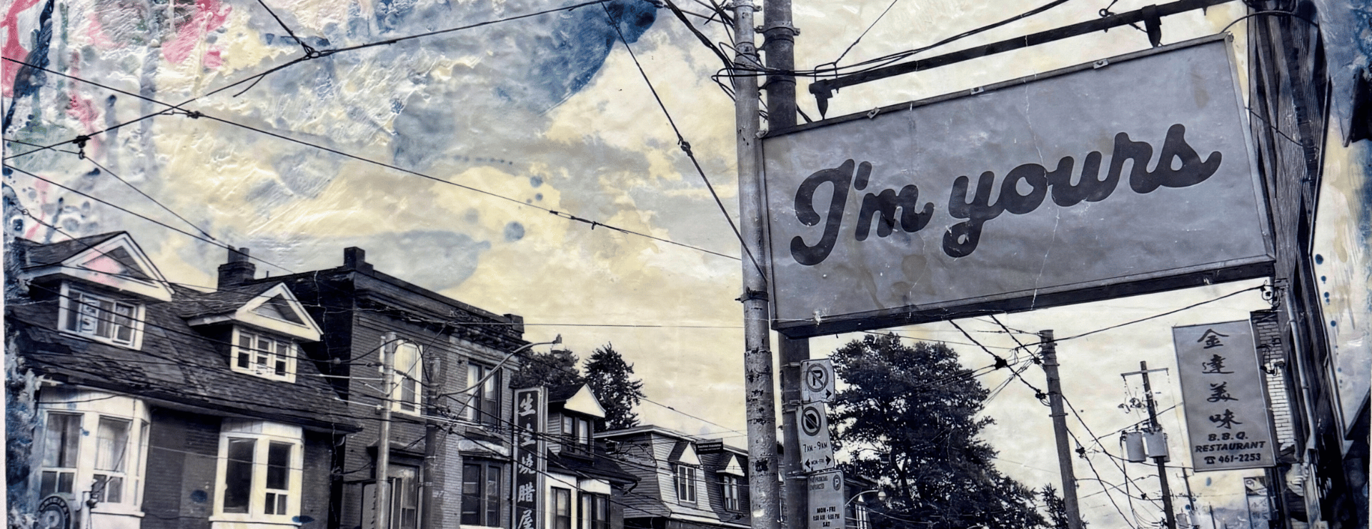 Black and white photograph of the text 
"I'm Yours" hanging from a sign with a row of urban Toronto buildings in the background. Spatters of paint and encaustic wax surround the image. 