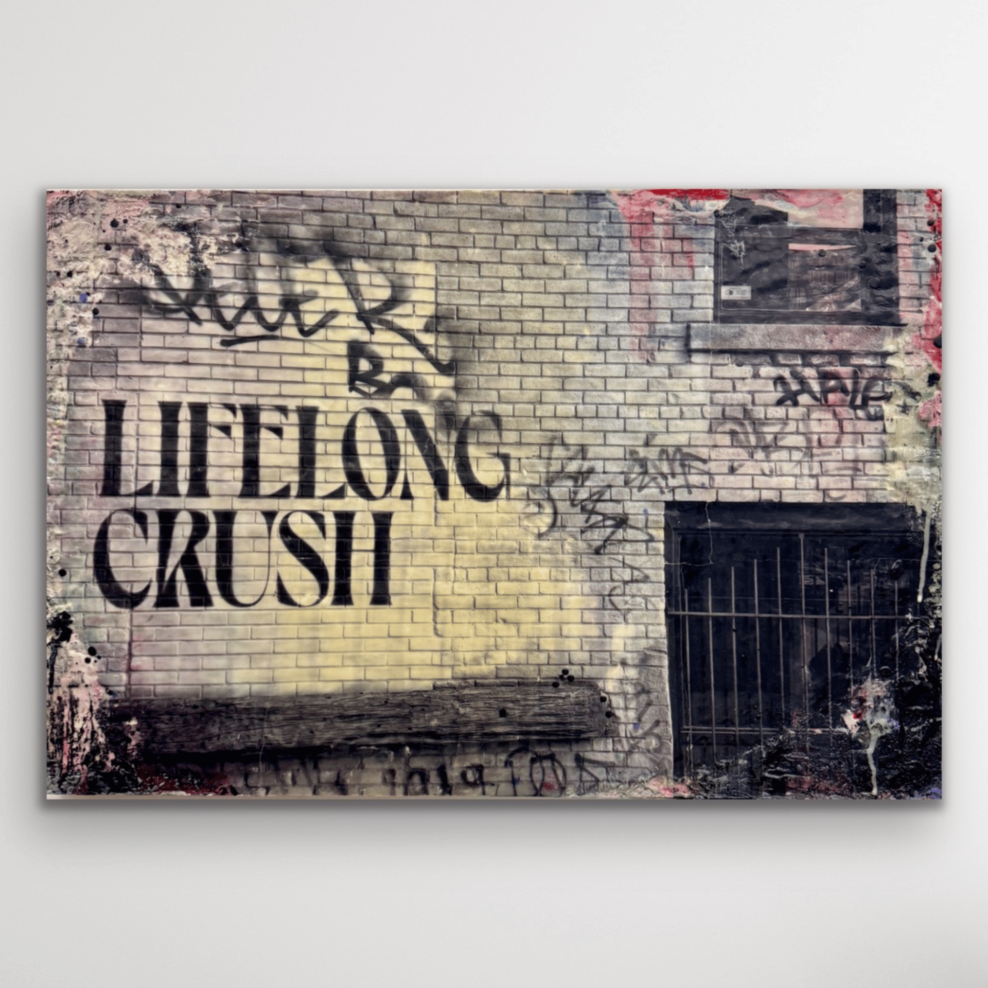 Black and white photograph of the text 
"lifelong crush" on a brick wall. Spatters of paint and encaustic wax surround the image. 
