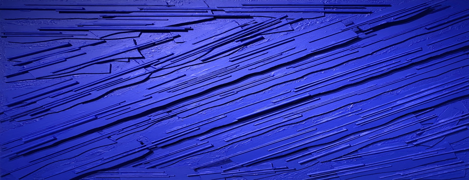 Deep blue sculptural piece made from woodcut techniques combined with acrylic paint