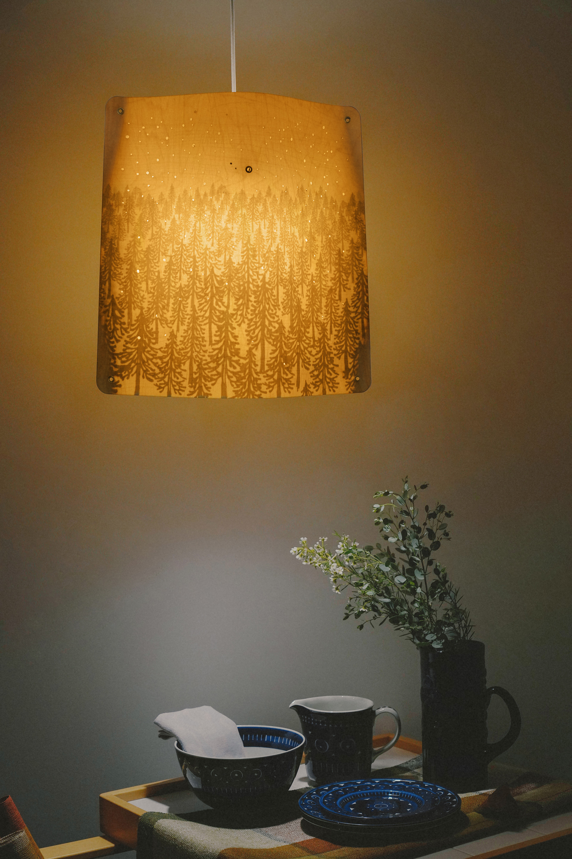 Birch pendant light with forest illustration suspended over set table