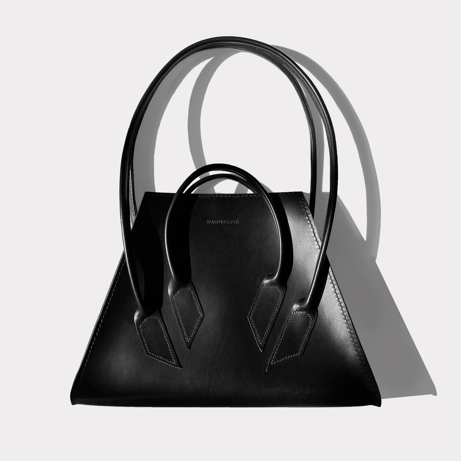 Black leather tote on gray background.