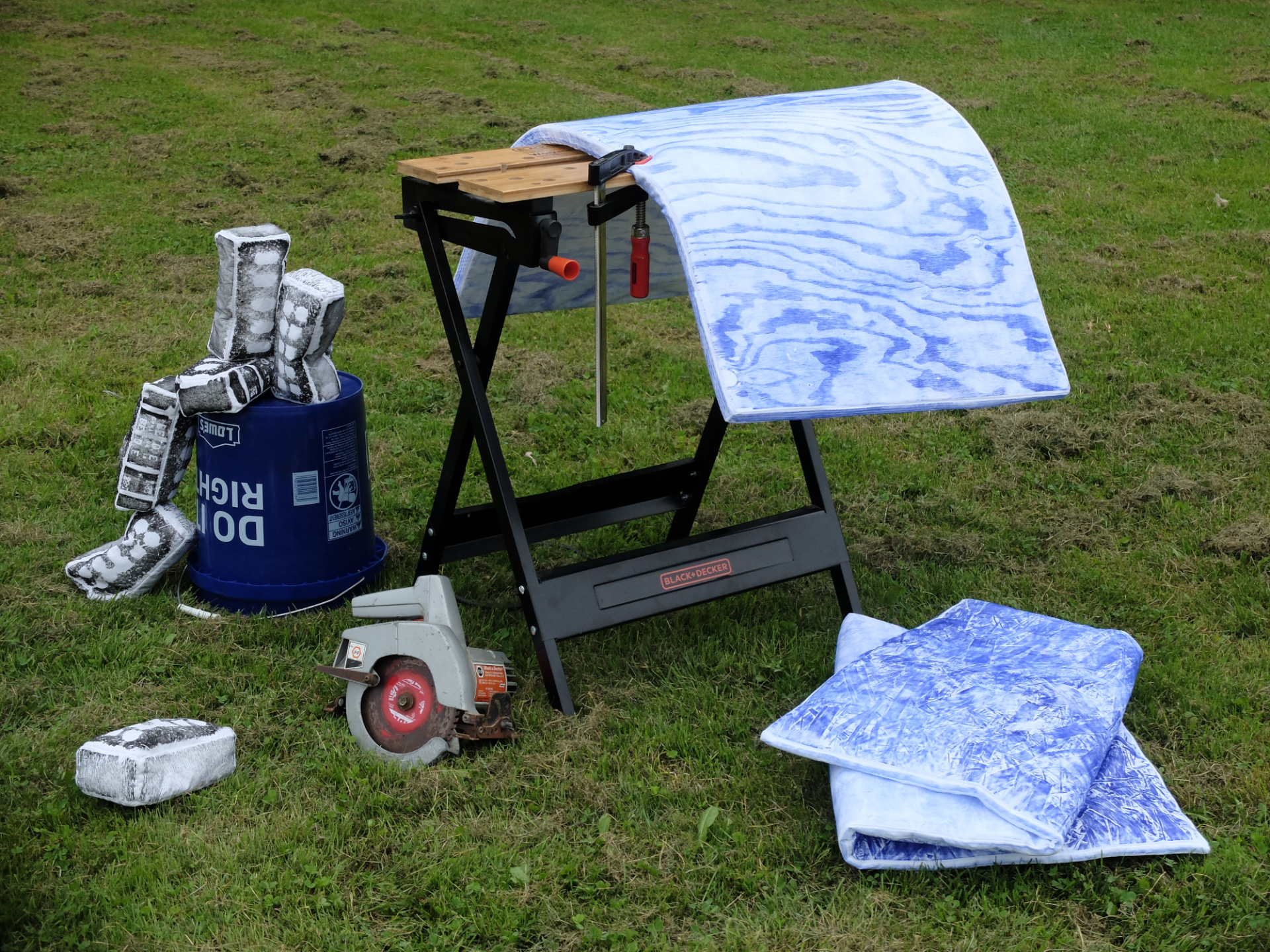 View of plush construction materials arranged with construction tools including a workbench, bucket, f-clamp and circular saw