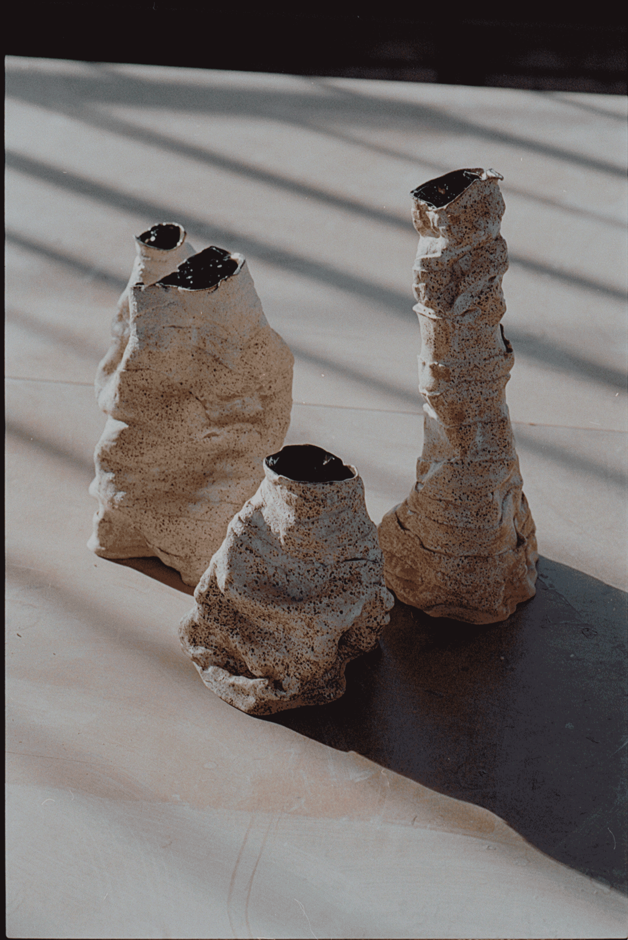 Arrangement of three handcrafted sculptural vases in varying heights made of speckled stoneware with mirrored black interior glazing