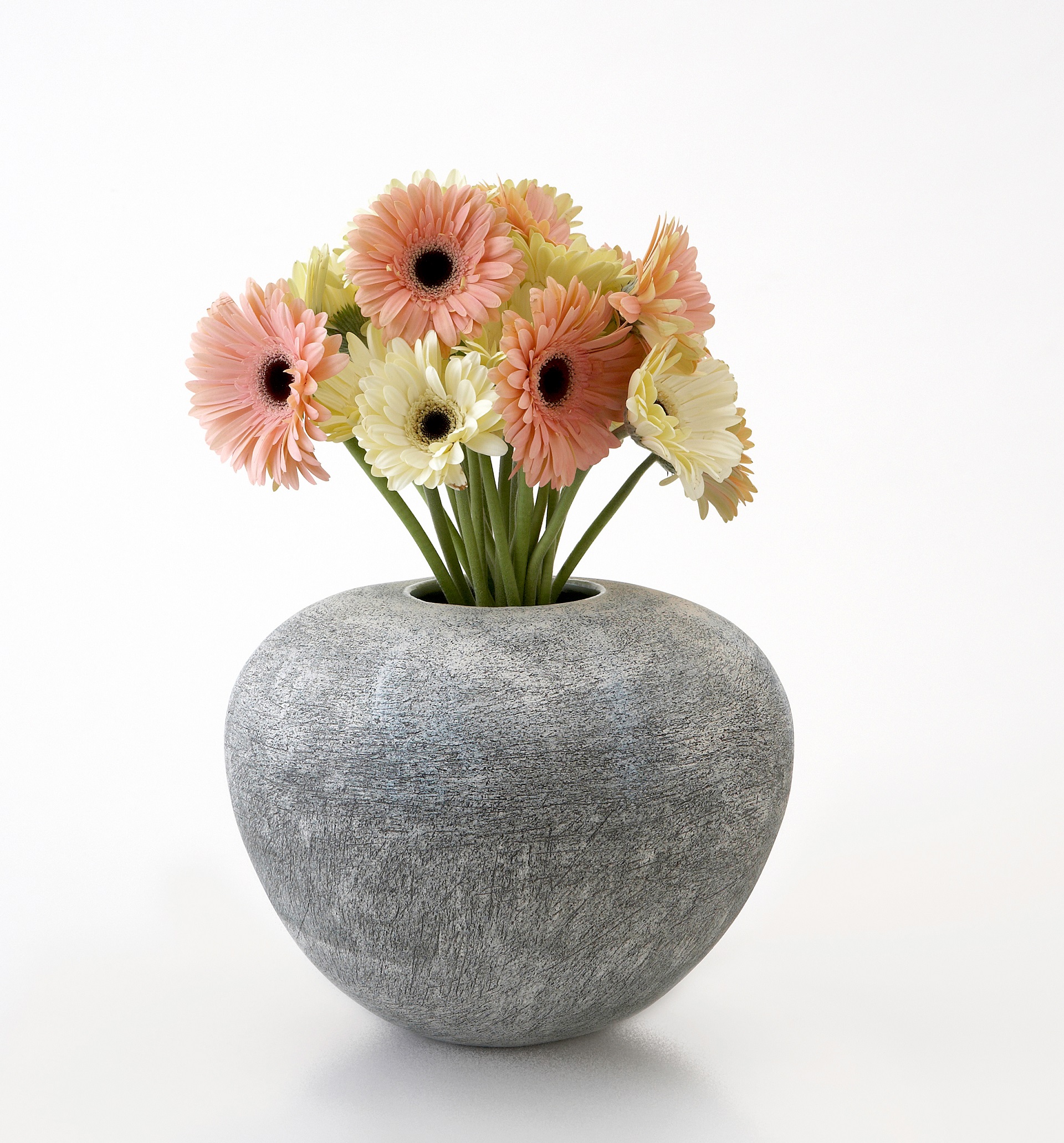 Grey rough texture on the exterior of a rounded vase with a small opening for flowers in the center at the top.