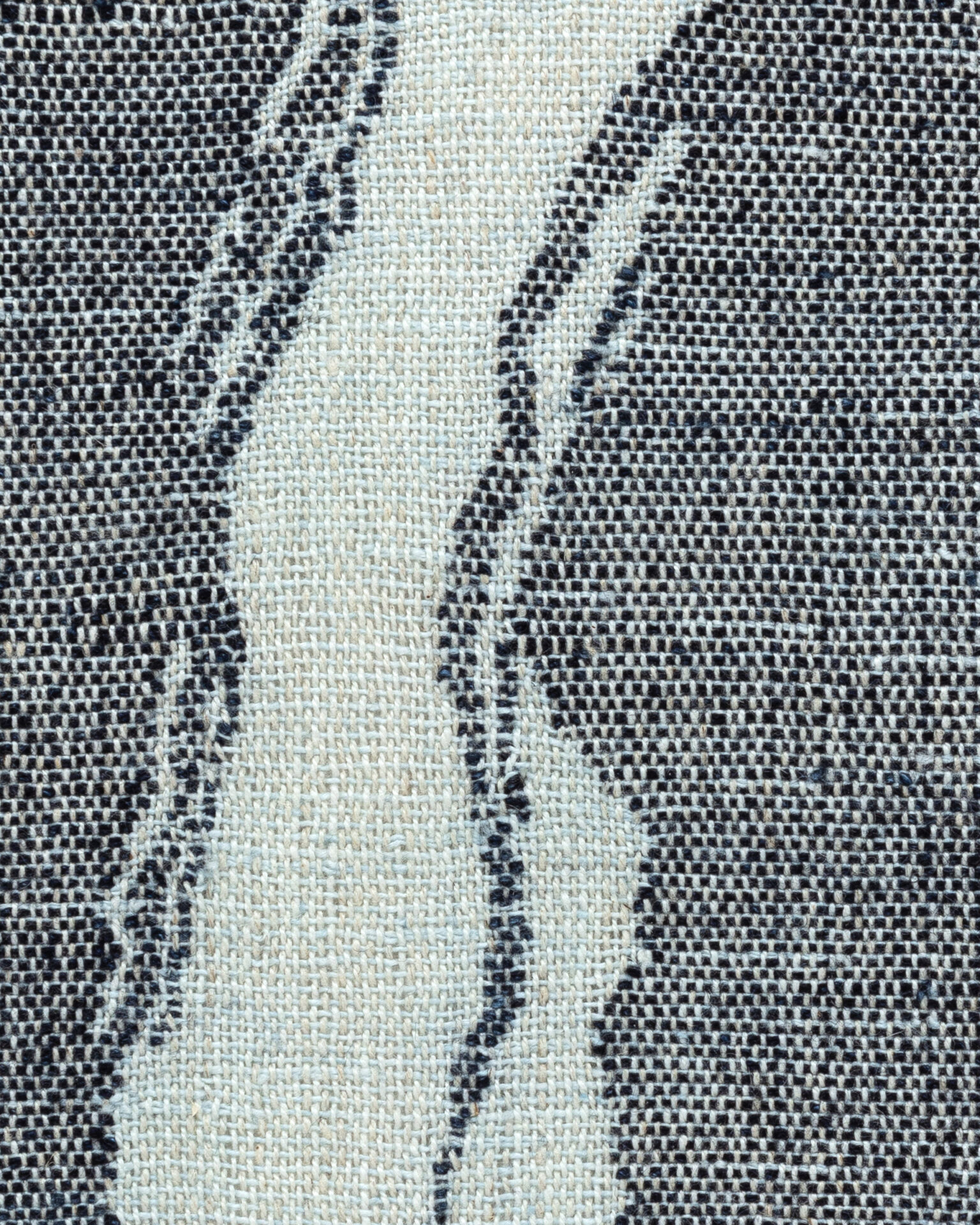Detail of abstract woven fabric art showing navy blue shapes in a pale blue cloth.