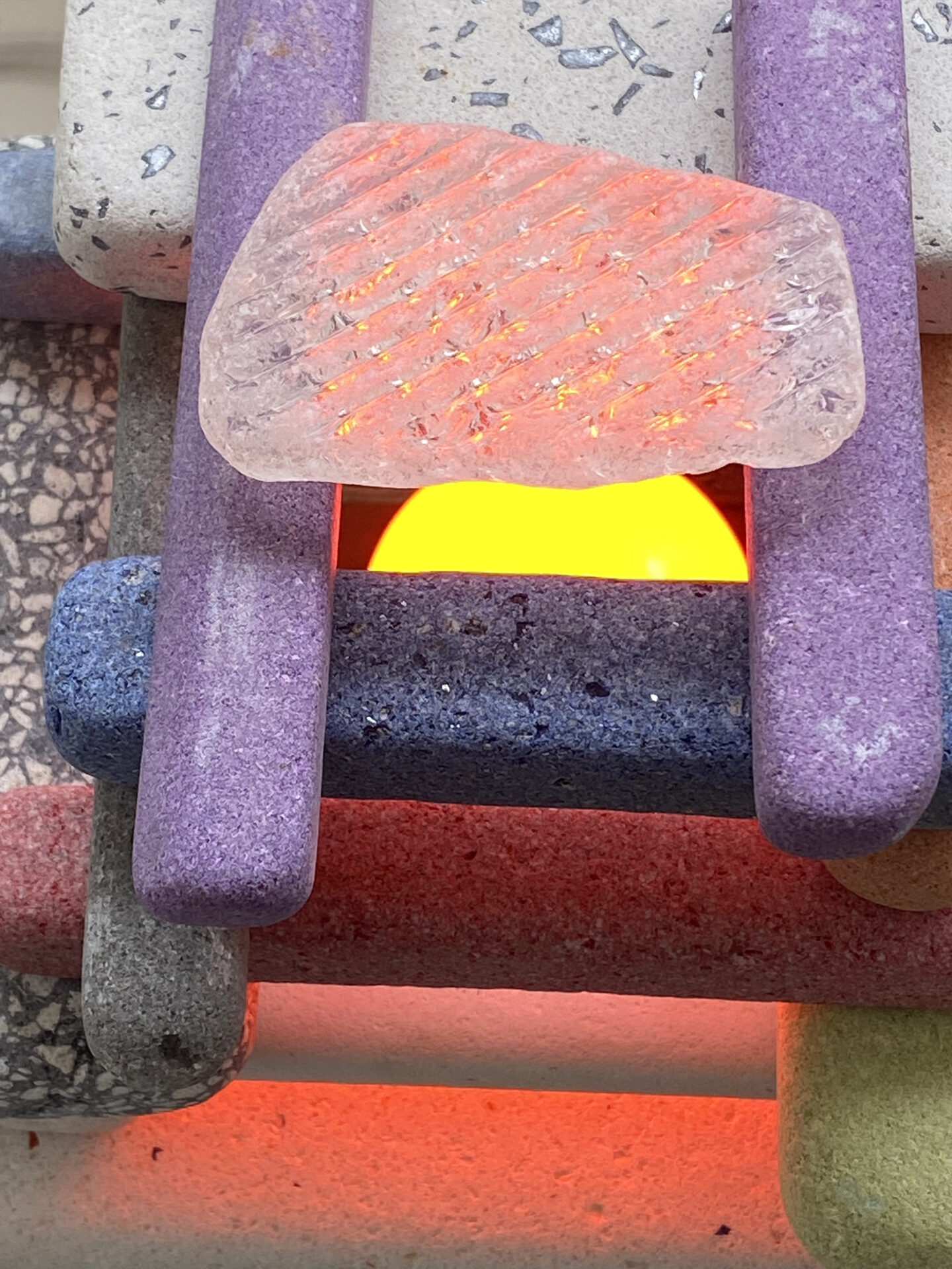 A light made from colourful stacked bricks, stones, and glass.