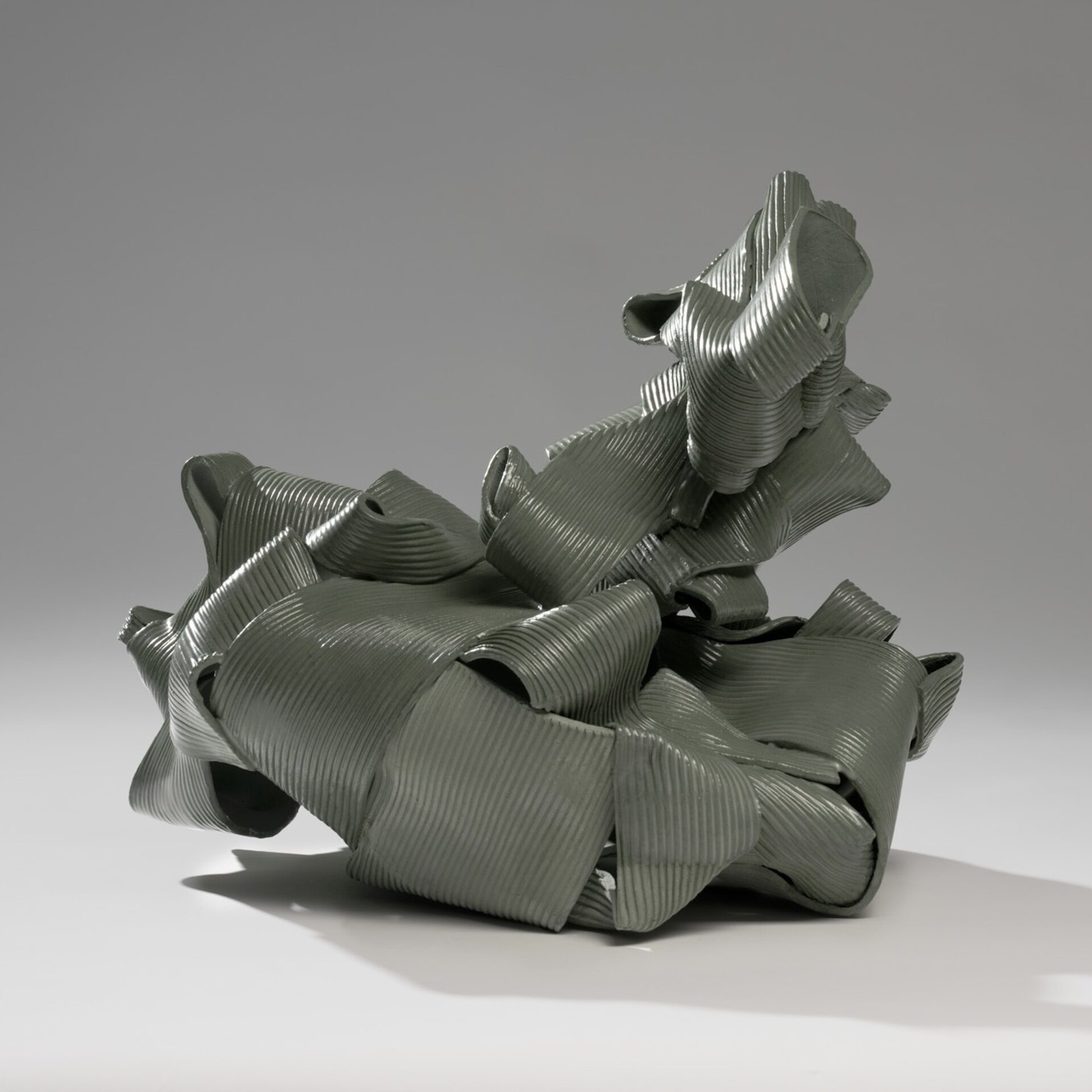 dark teal ceramic sculpture made with ribbon-like strips of textured clay