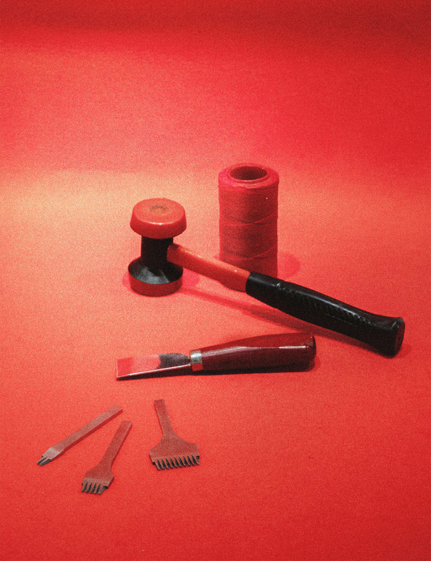Arrangement of leatherworking tools - thread, mallet, knife, prong.