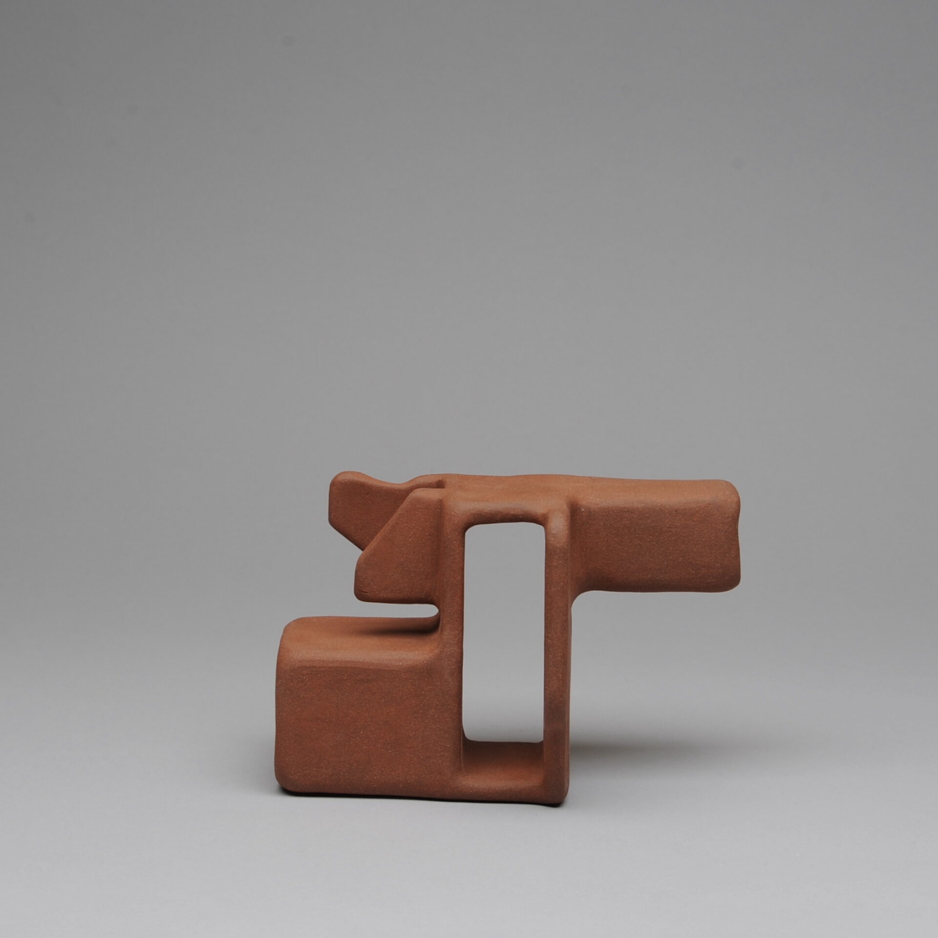 One red piece of a three part stacking sculpture with angular shapes