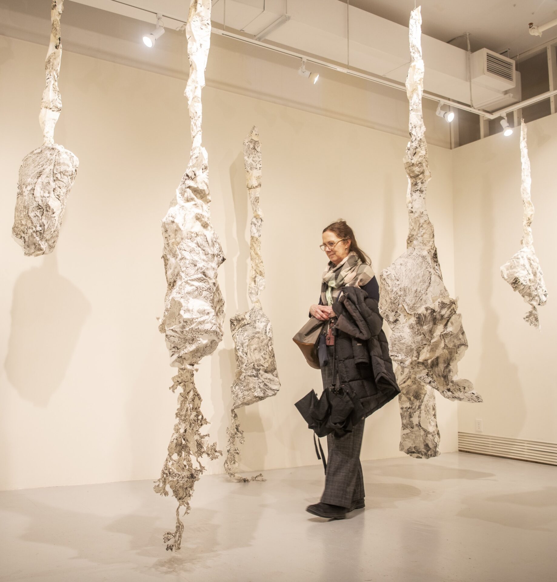 Person walking in between hanging paper sculptures.