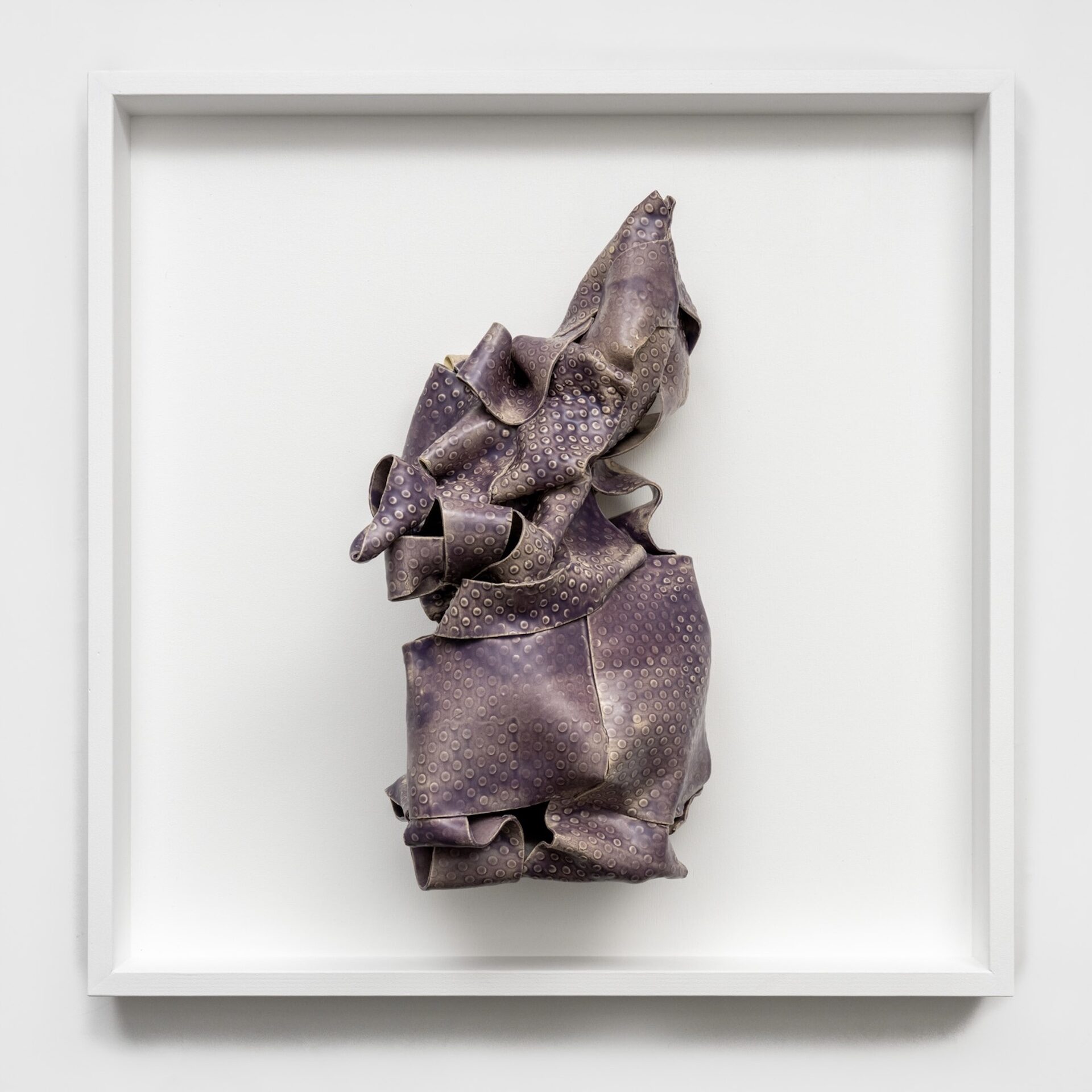 dark purple ceramic sculpture of dot textured clay strips mounted on an open wood frame