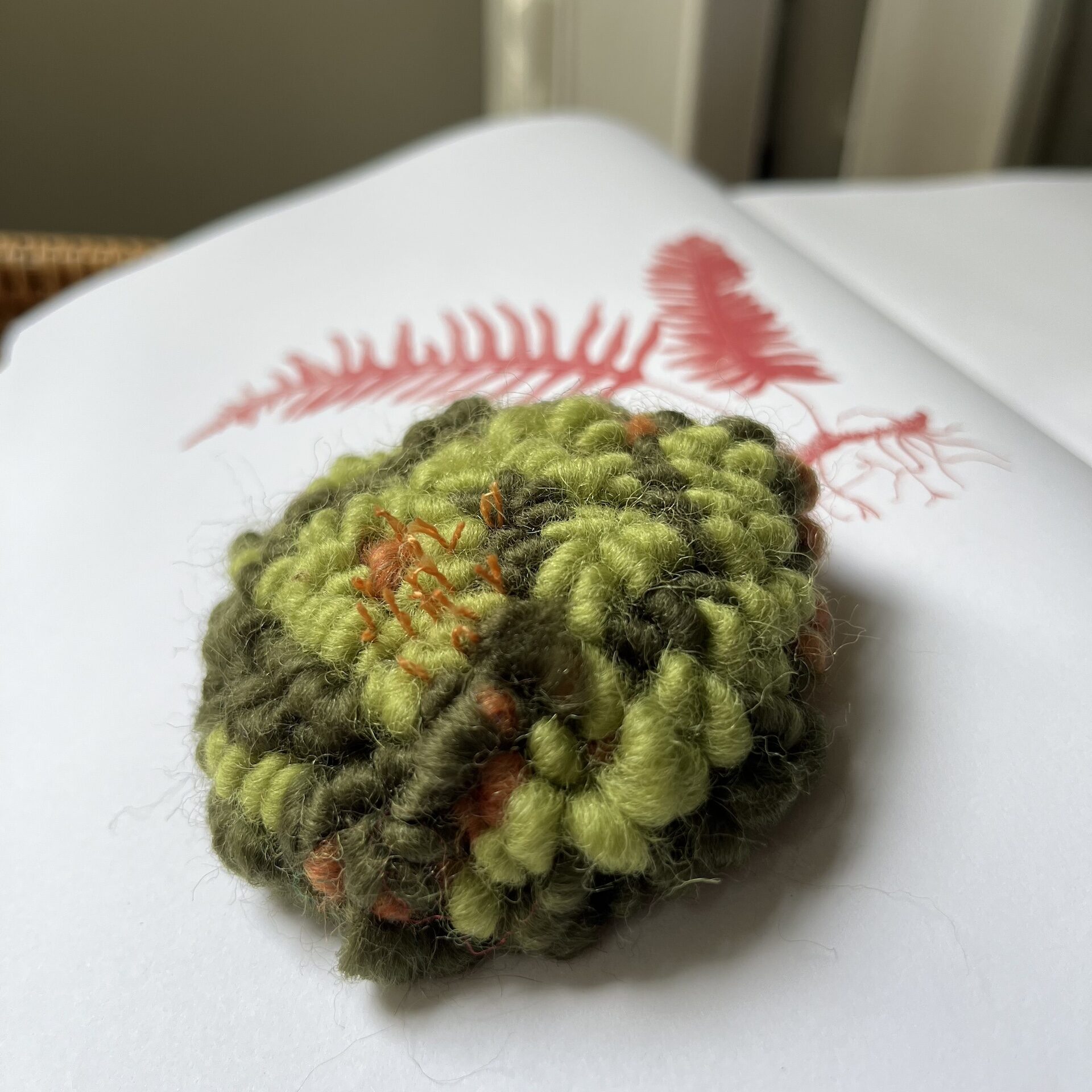 Rug hooked grassy knoll in green and brown yarns