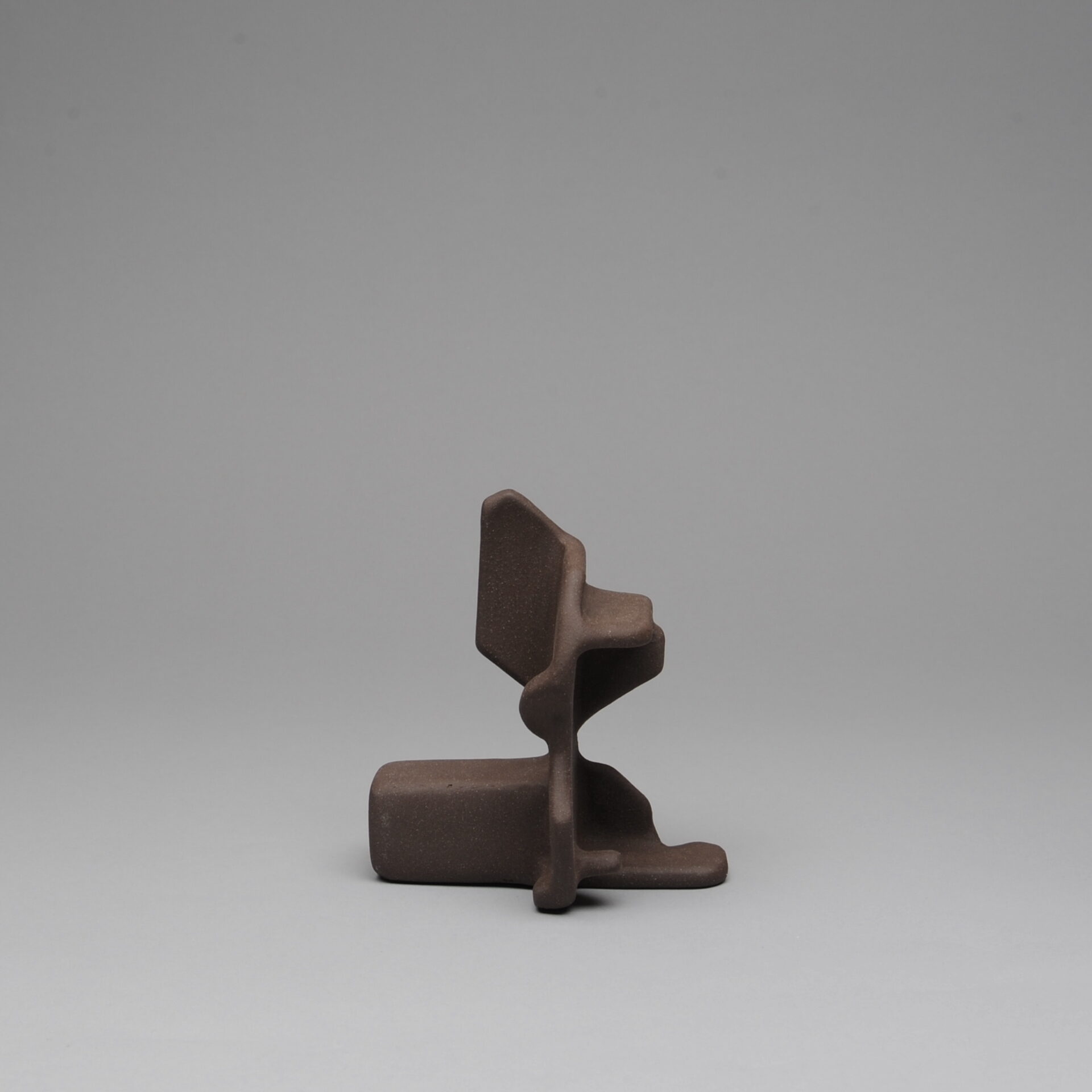 One brown piece of a three part stacking sculpture with angular shapes
