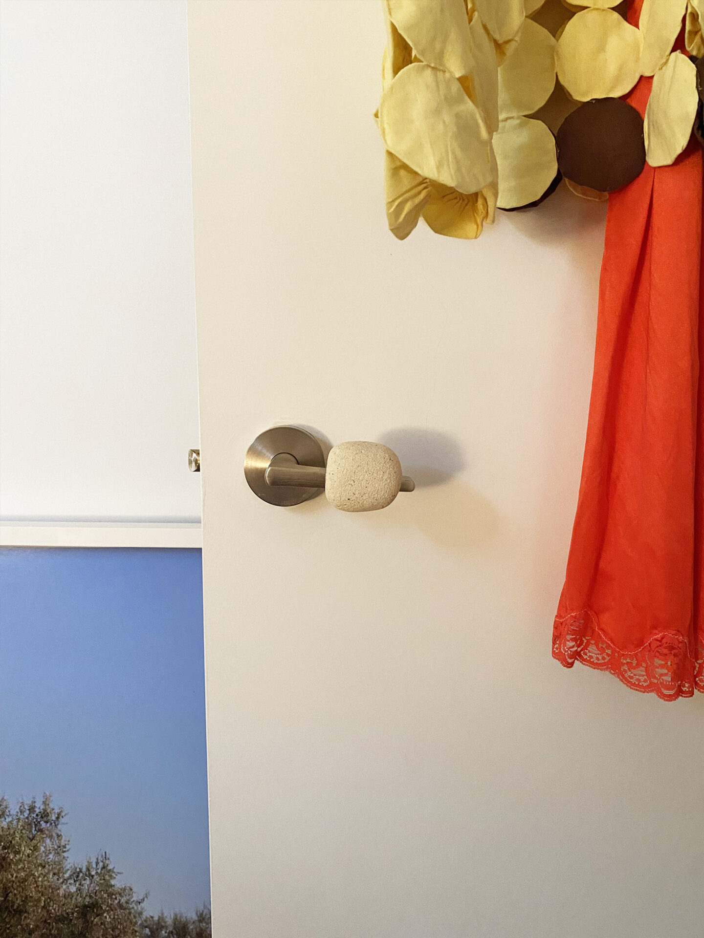 A small white stone is stuck onto a metal door handle, creating a stone doorknob.